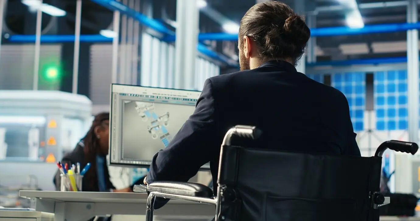 Человек с инвалидностью инспектирует оборудование солнечной электростанции на экране компьютера.